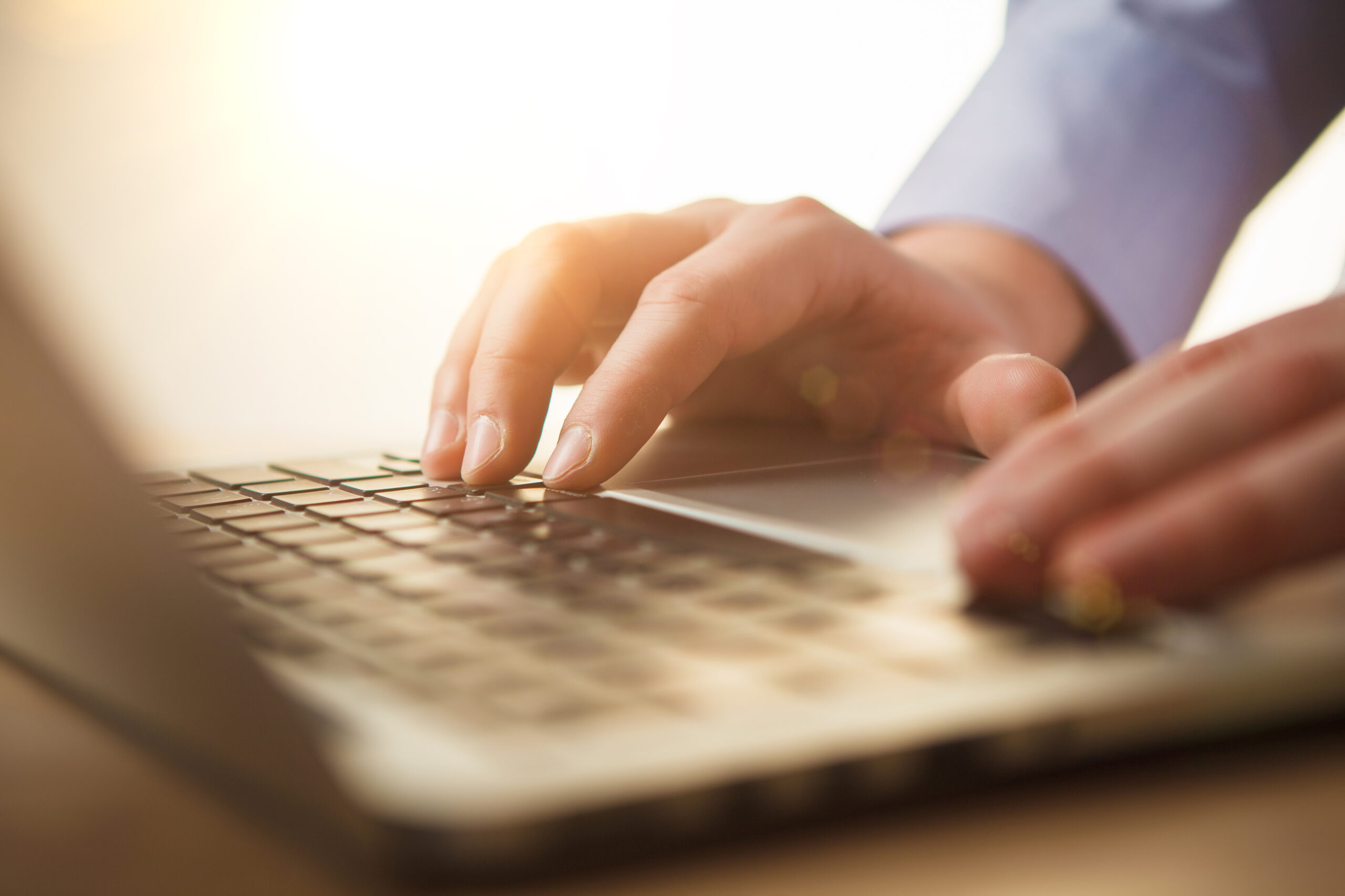 The male hands on the keyboard on the background of table